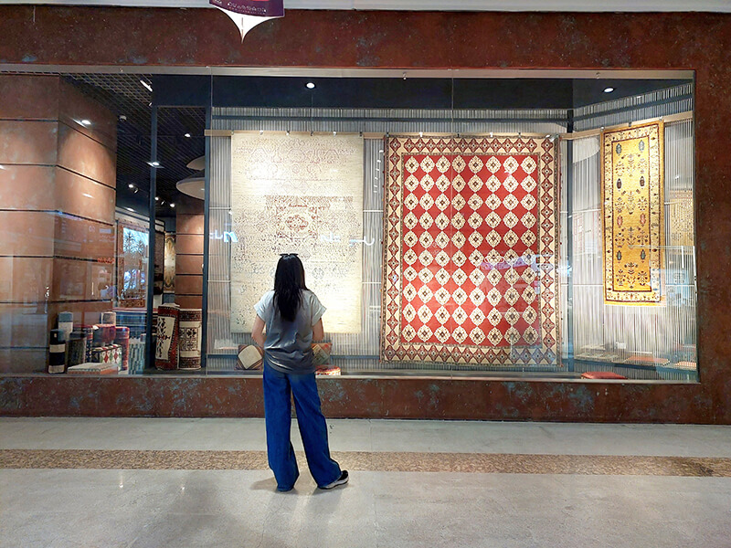 Compassimo-Local woman amazed by Persian Carpet in a Mall in Tehran