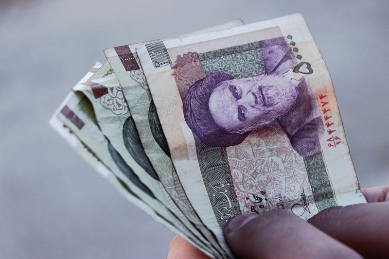 Compassimo-Detailed view of Iranian rial banknotes held in hand